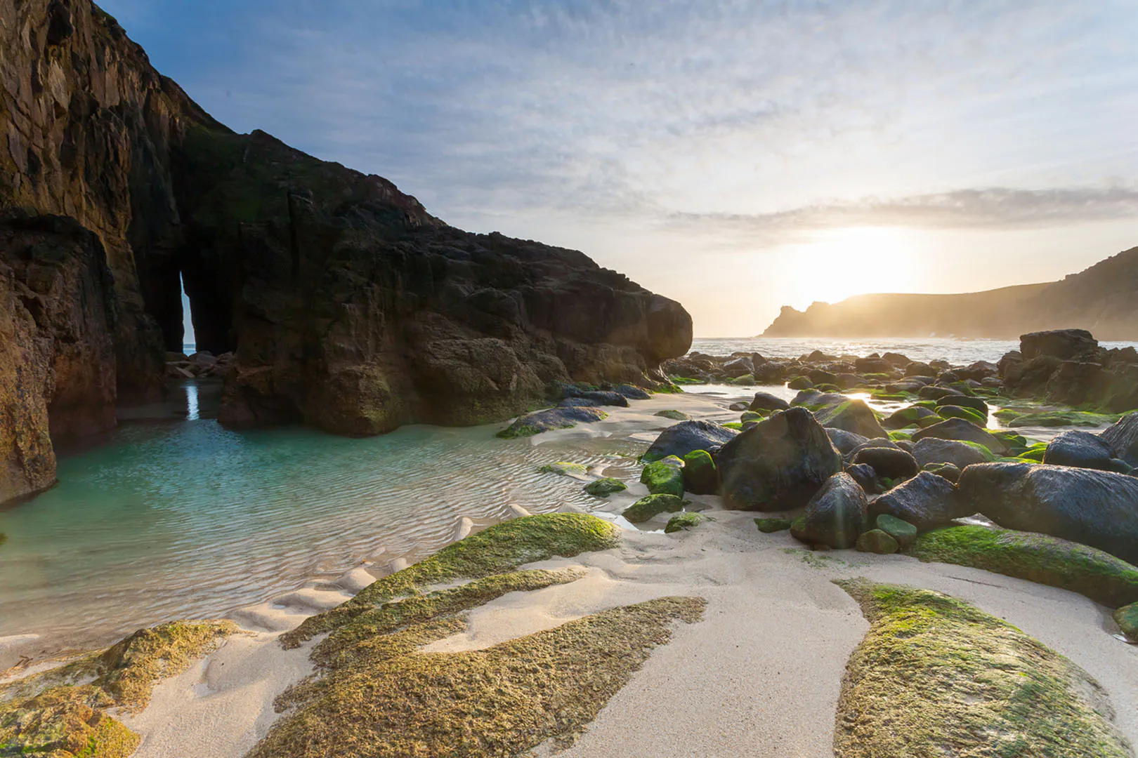 Sunset over Nanjizal Beach, showcasing rocky shores and gentle waves, perfect for swimming in Cornwall's scenic coastline.