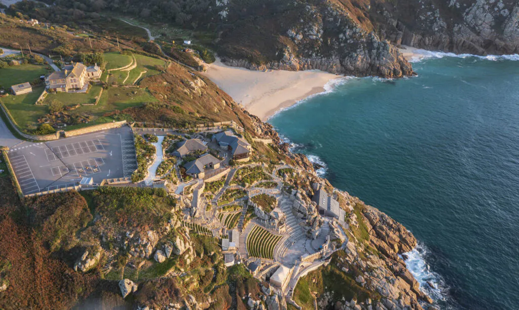 Aerial drone landscape image of Minnack Theatre headland around Porthcurno beach in Cornwall England at dawn